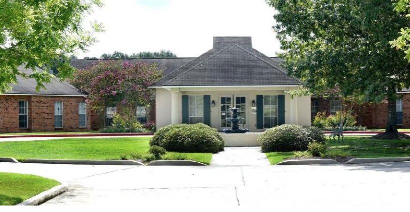 Grass and trees surrounding the architectural buildings of Oakwood Village, a senior living community.