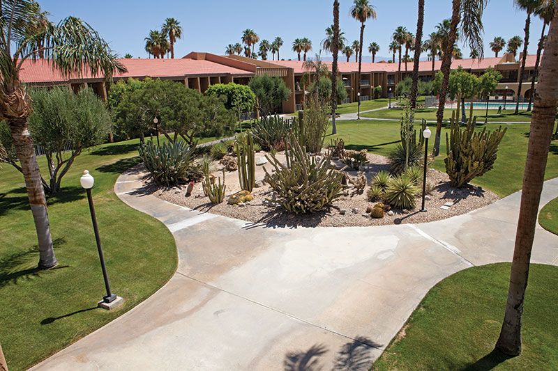 Senior living community, The Carlotta, Ivy Signature Living, featuring lush park and villa.